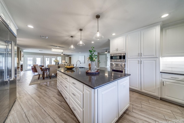 kitchen with white cabinetry, built in appliances, and ceiling fan