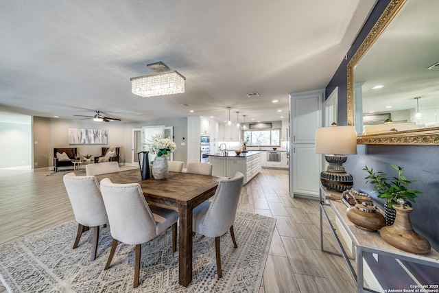 dining area featuring ceiling fan with notable chandelier and sink