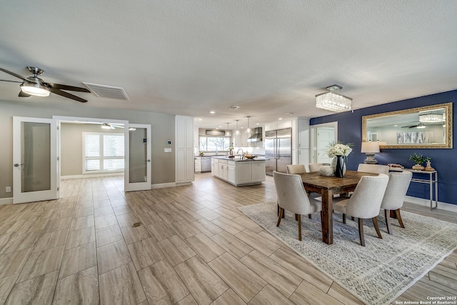 unfurnished dining area featuring ceiling fan, french doors, a healthy amount of sunlight, and sink