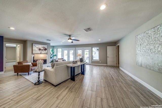 living room with ceiling fan, french doors, and a textured ceiling