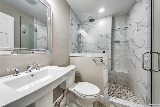 bathroom featuring sink, a shower with shower door, and toilet