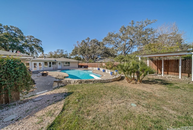 view of pool with french doors, a patio area, and a lawn