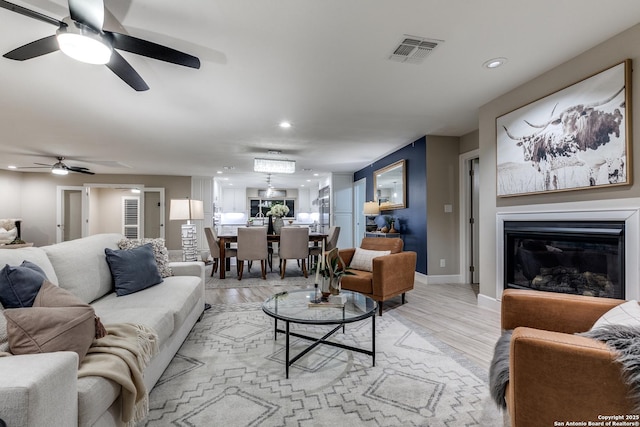 living room with ceiling fan and light wood-type flooring