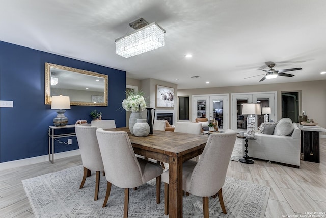 dining room with light wood-type flooring and ceiling fan with notable chandelier