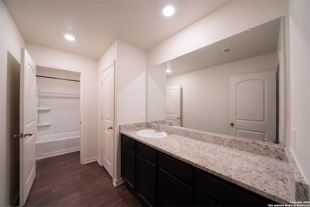 bathroom featuring hardwood / wood-style flooring, vanity, and bathing tub / shower combination