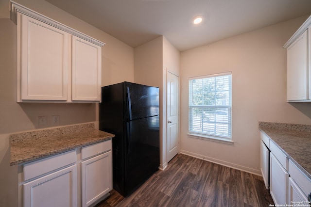 kitchen with black fridge, dark hardwood / wood-style floors, white cabinets, and light stone countertops