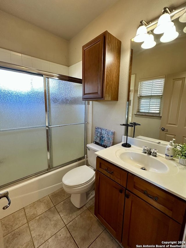 full bathroom featuring tile patterned floors, vanity, enclosed tub / shower combo, and toilet