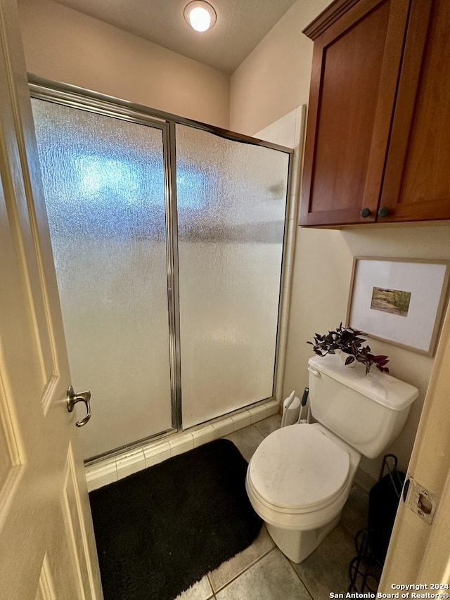 bathroom with tile patterned flooring, toilet, and an enclosed shower