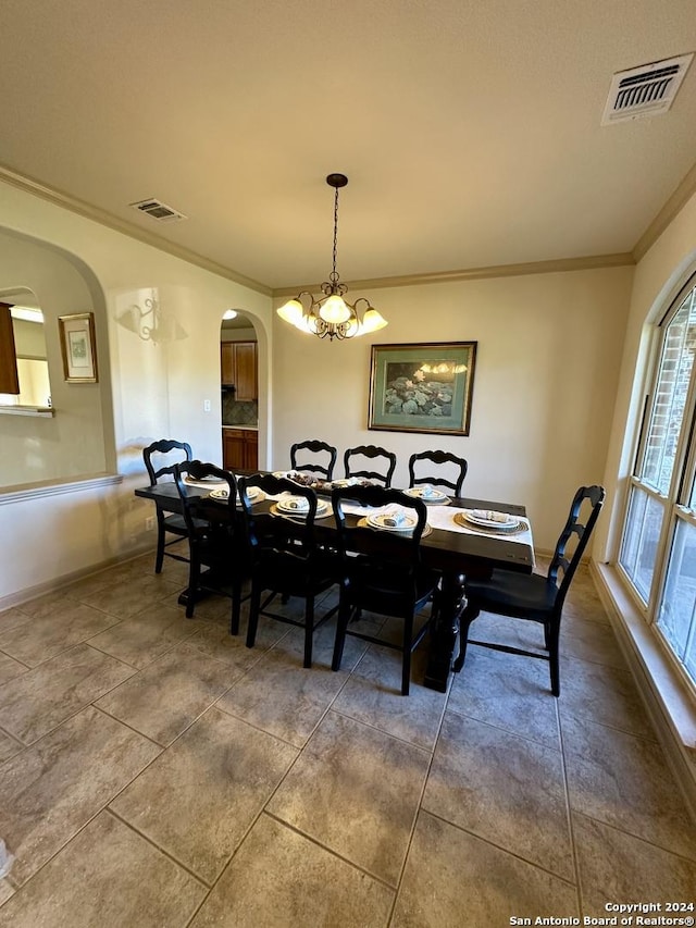 tiled dining room with a chandelier and ornamental molding