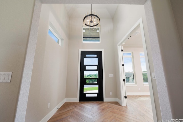 entrance foyer with a notable chandelier, a high ceiling, and light parquet floors