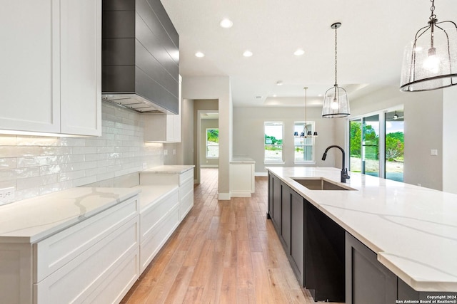 kitchen with decorative light fixtures, white cabinetry, a spacious island, and sink