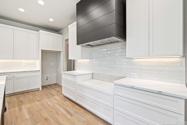 kitchen with custom exhaust hood, light wood-type flooring, white cabinetry, and light stone counters