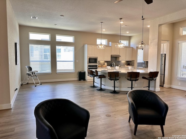 interior space with built in microwave, a breakfast bar, hanging light fixtures, and light hardwood / wood-style floors