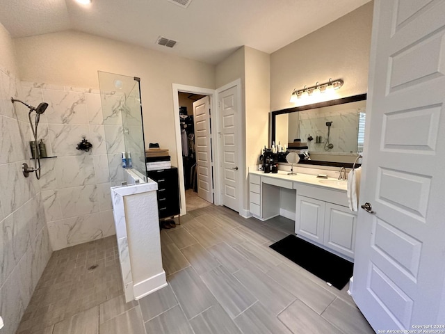 bathroom with a tile shower and vanity