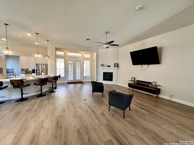 living room featuring sink, light wood-type flooring, ceiling fan, and a premium fireplace