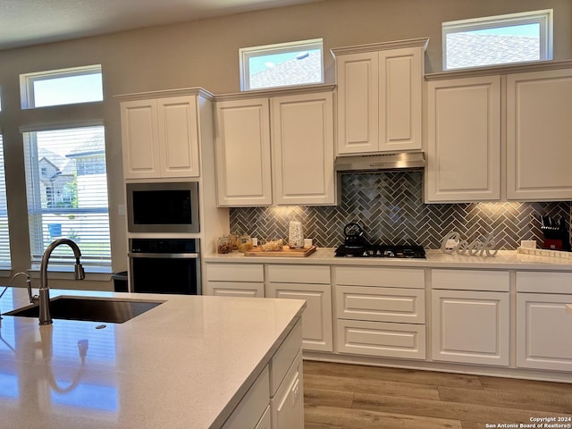 kitchen featuring built in microwave, stainless steel oven, plenty of natural light, and sink