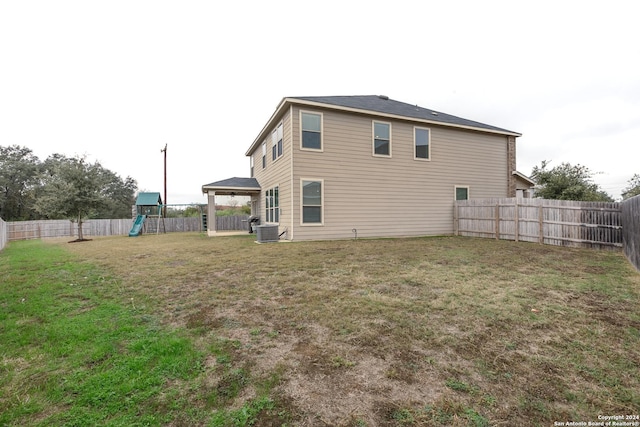 back of house featuring a yard, a playground, and central air condition unit