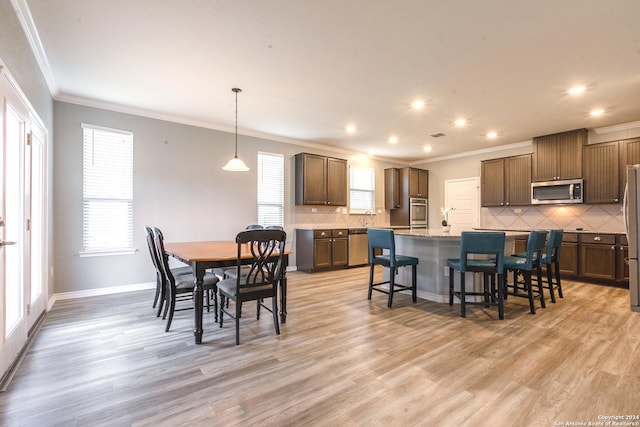 dining area with light hardwood / wood-style floors and crown molding