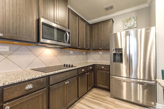 kitchen featuring backsplash, light stone countertops, dark brown cabinets, and appliances with stainless steel finishes