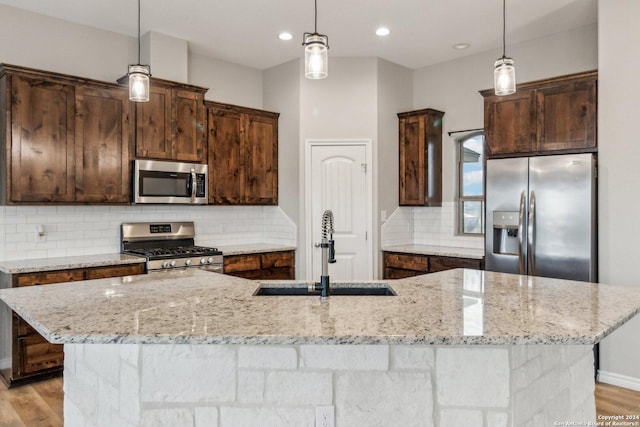 kitchen with pendant lighting, a large island with sink, sink, and appliances with stainless steel finishes