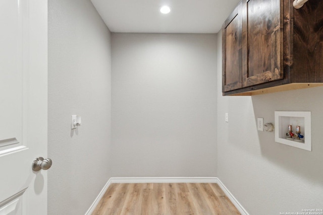 clothes washing area featuring cabinets, washer hookup, and light hardwood / wood-style floors