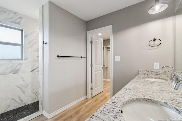 bathroom with hardwood / wood-style floors, vanity, and tiled shower