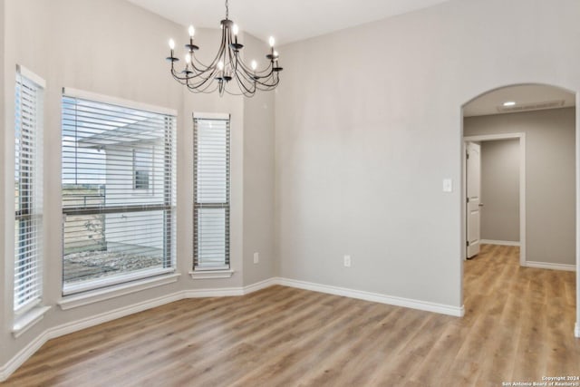 spare room with light hardwood / wood-style floors, a wealth of natural light, and a notable chandelier