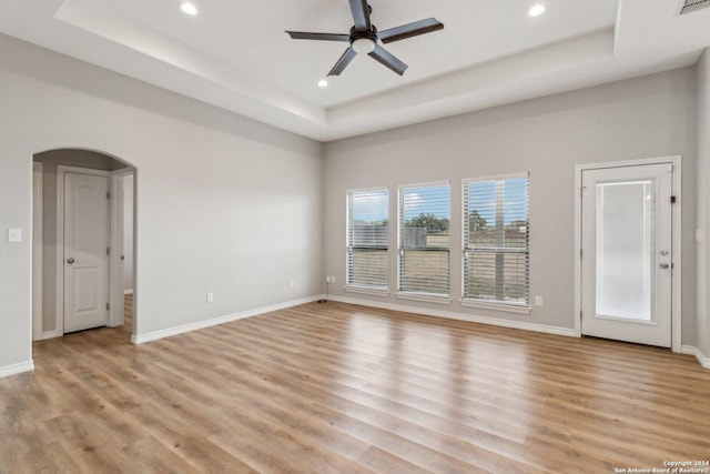 unfurnished living room featuring a tray ceiling, light hardwood / wood-style flooring, and ceiling fan