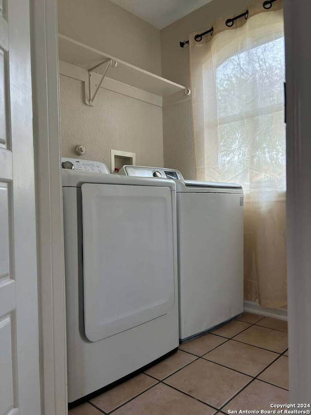 washroom with washing machine and clothes dryer and light tile patterned floors