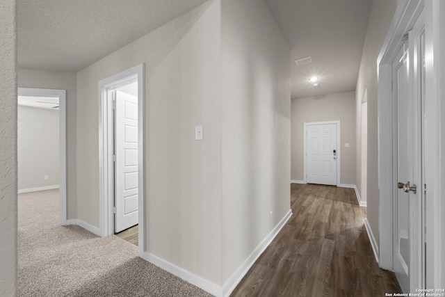 hallway with dark wood-type flooring and a textured ceiling