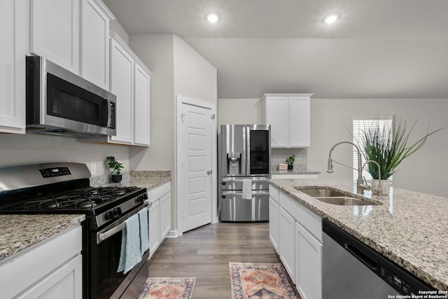 kitchen featuring sink, dark hardwood / wood-style floors, appliances with stainless steel finishes, light stone counters, and white cabinetry