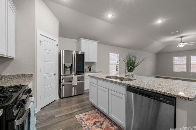 kitchen with lofted ceiling, white cabinets, sink, light stone counters, and stainless steel appliances