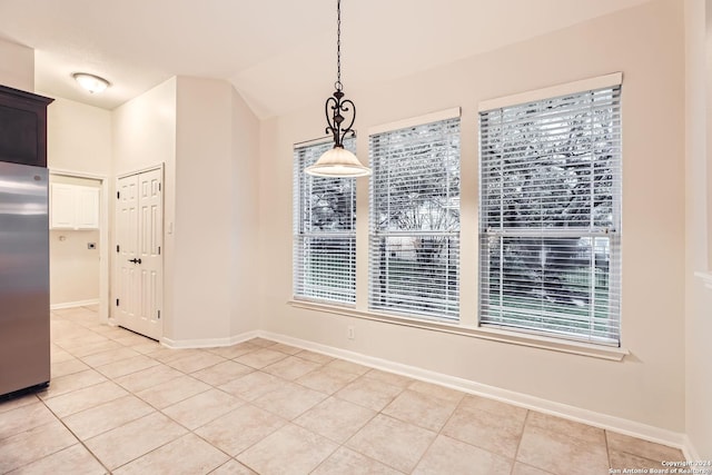 unfurnished dining area featuring light tile patterned floors and vaulted ceiling