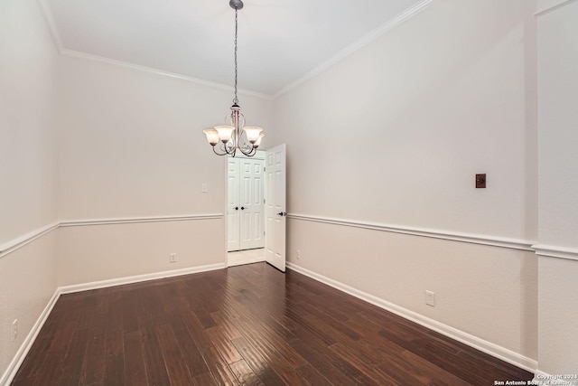 empty room featuring dark hardwood / wood-style flooring, ornamental molding, and an inviting chandelier