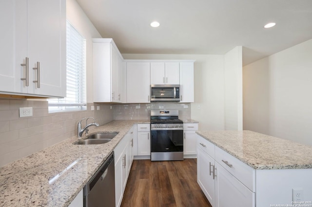 kitchen with light stone countertops, sink, white cabinets, and appliances with stainless steel finishes