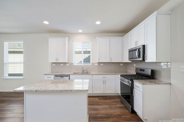 kitchen featuring white cabinets, light stone counters, dark wood-type flooring, and appliances with stainless steel finishes