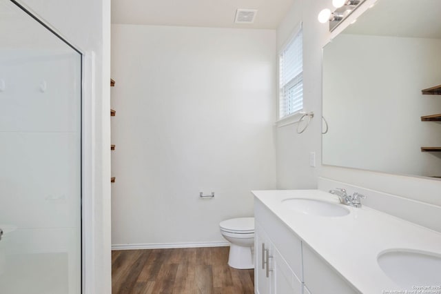 bathroom featuring vanity, toilet, wood-type flooring, and a shower with door