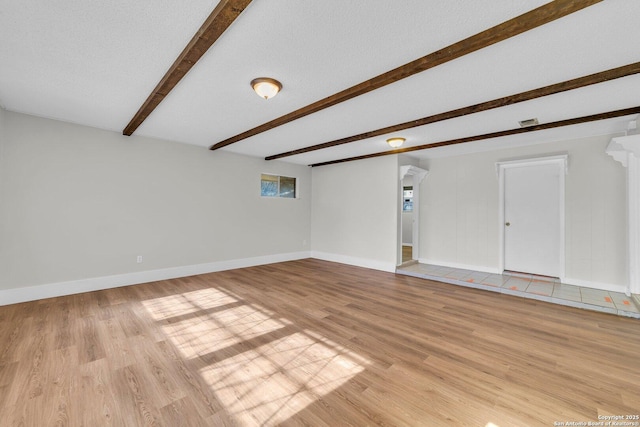 interior space featuring beam ceiling, a textured ceiling, and light wood-type flooring