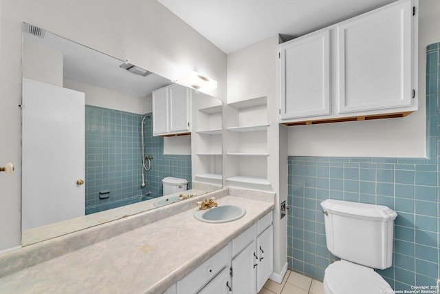 bathroom featuring tile patterned flooring, vanity, toilet, and tile walls