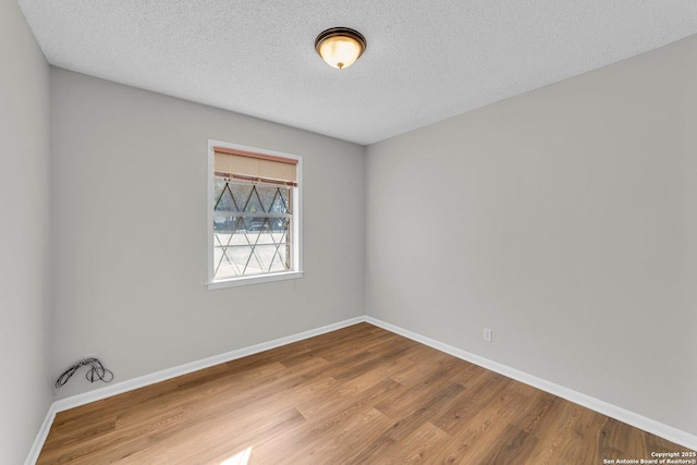 empty room with a textured ceiling and light hardwood / wood-style flooring