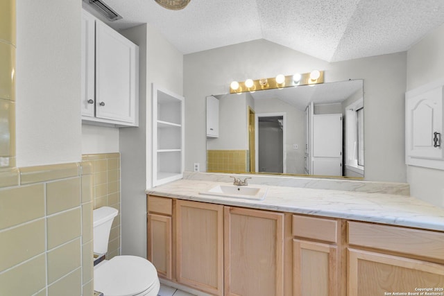 bathroom featuring a textured ceiling, vanity, lofted ceiling, and toilet