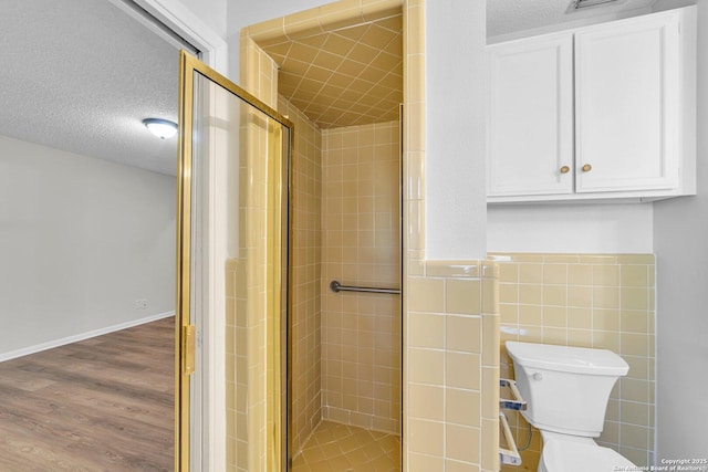 bathroom featuring hardwood / wood-style floors, a textured ceiling, walk in shower, and tile walls