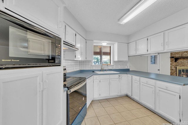 kitchen with a fireplace, white cabinetry, black appliances, and sink