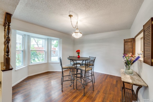 dining room with dark wood-type flooring, a textured ceiling, and a chandelier