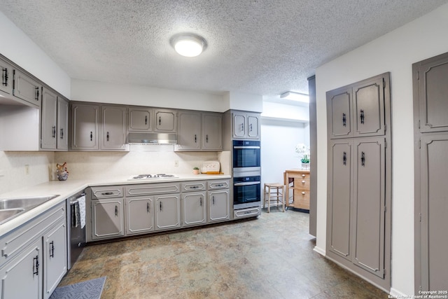 kitchen with a textured ceiling, appliances with stainless steel finishes, sink, and gray cabinets