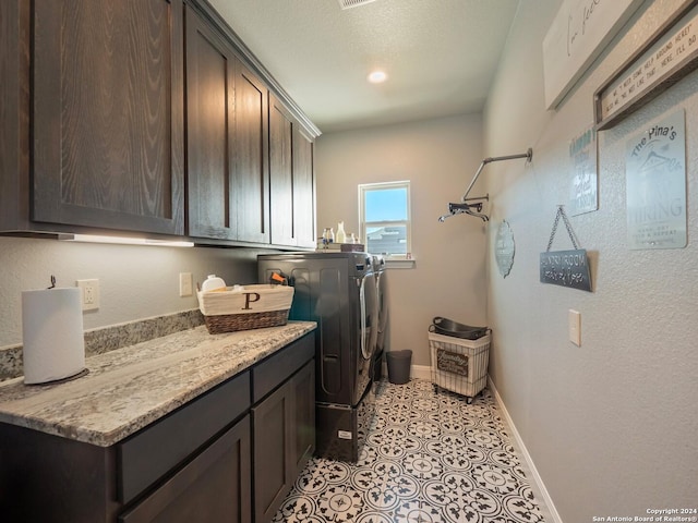 laundry area featuring washing machine and dryer, light tile patterned floors, and cabinets