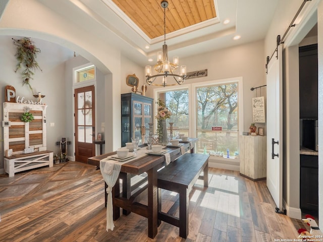 dining space featuring an inviting chandelier, a barn door, hardwood / wood-style floors, a tray ceiling, and wood ceiling