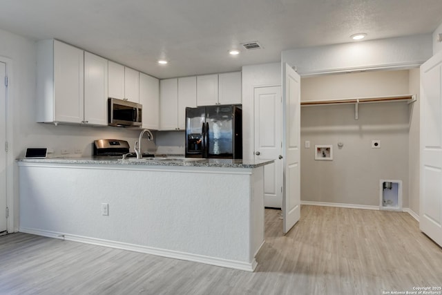 kitchen featuring light wood-type flooring, appliances with stainless steel finishes, stone countertops, and white cabinetry