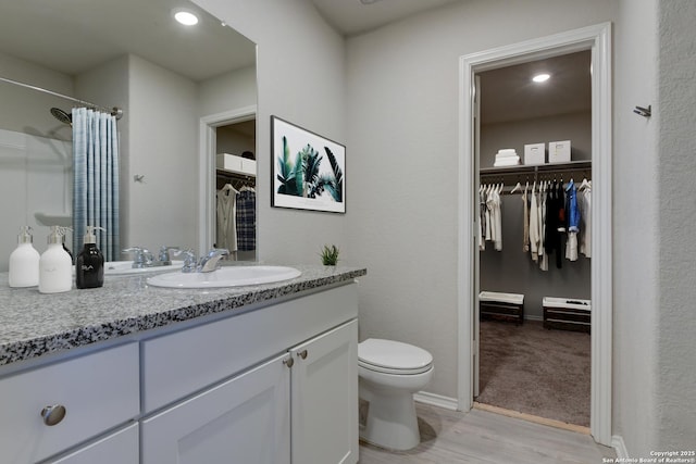 bathroom featuring wood-type flooring, toilet, vanity, and walk in shower