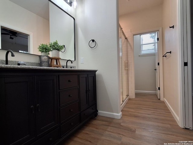 bathroom with hardwood / wood-style floors, vanity, ceiling fan, and walk in shower